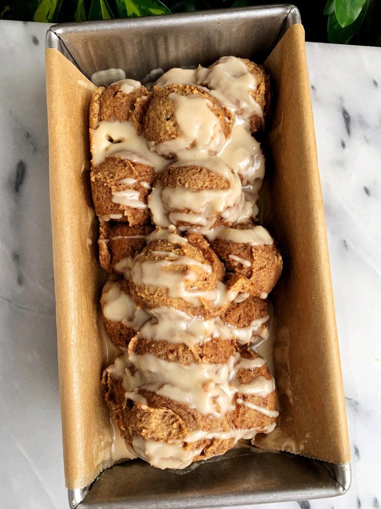 vegan monkey bread in a baking dish drizzled with frosting