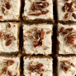 vegan carrot cake cut into squares topped with frosting and nuts