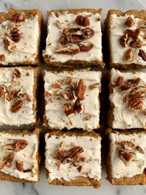 vegan carrot cake cut into squares topped with frosting and nuts
