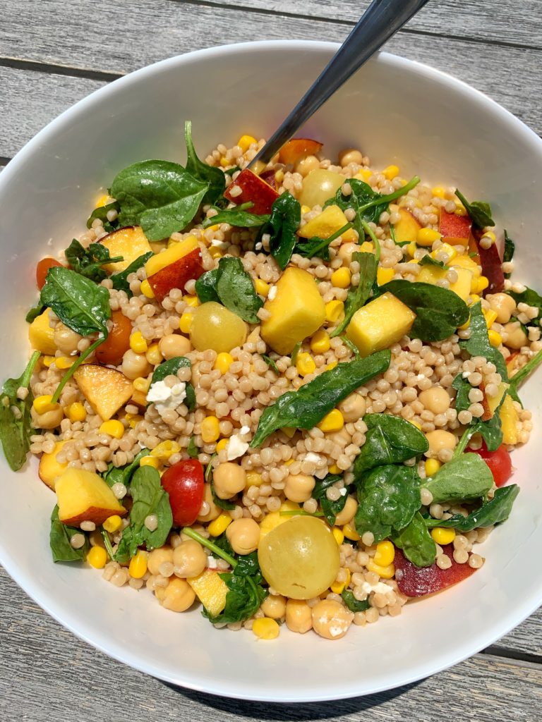 The best summertime couscous salad filled with fresh ingredients like cherry tomatoes, peaches, corn, leafy greens and more. This healthy and easy BBQ side dish has become a family and friend favorite and it is an easy vegetarian dish to make!