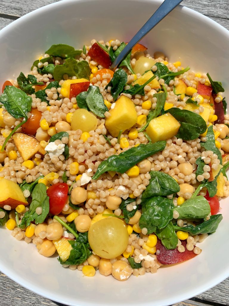 The best summertime couscous filled with fresh ingredients like cherry tomatoes, peaches, corn, leafy greens and more. This healthy and easy BBQ side dish has become a family and friend favorite and it is an easy vegetarian dish to make!