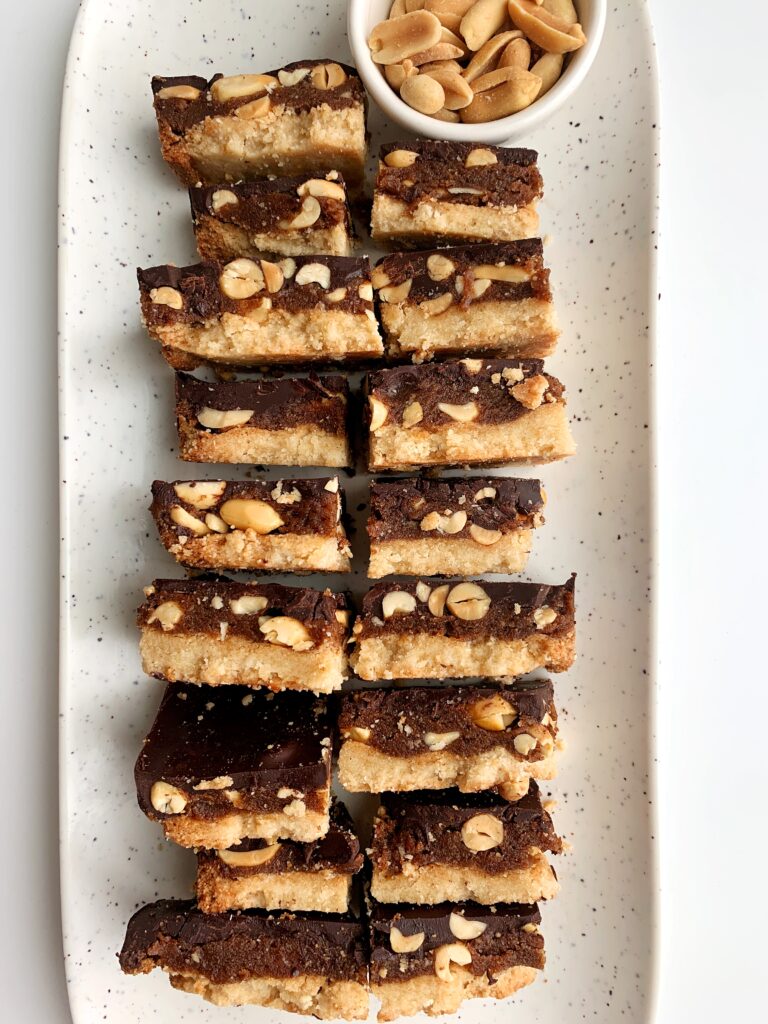 Copycat Vegan "Snickers" Candy Bars made with all grain-free, gluten-free and paleo-friendly ingredients. These are the dreamiest and easiest healthier snickers recipe with a cookie base, caramel center with crushed peanuts and covered in chocolate. 