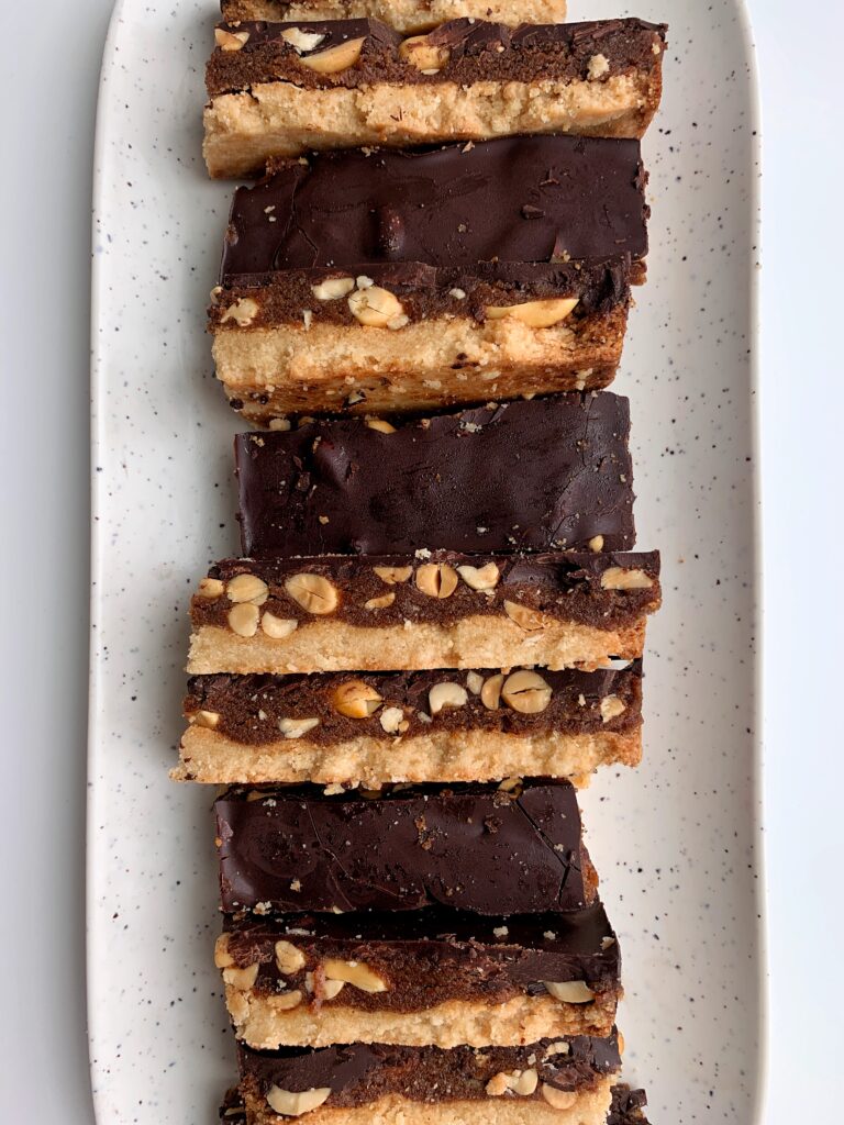 Copycat Vegan "Snickers" Candy Bars made with all grain-free, gluten-free and paleo-friendly ingredients. These are the dreamiest and easiest healthier snickers recipe with a cookie base, caramel center with crushed peanuts and covered in chocolate. 