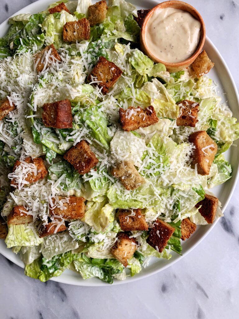The Best Healthy Classic Caesar Salad with homemade caesar dressing, baked sourdough croutons on top of crunchy romaine with a sprinkle of fresh parmesan cheese.