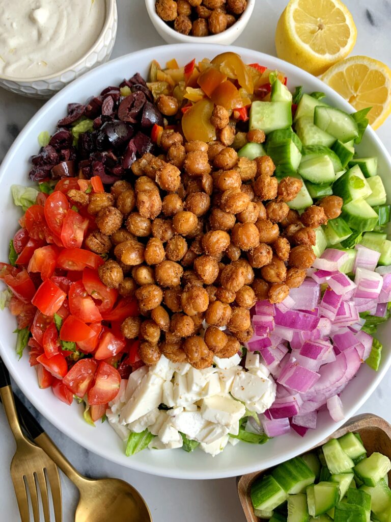 This Vegetarian Greek Salad with Tahini Yogurt Dressing is filled with all your Greeks salad favorites plus it's topped with crispy chickpeas and tossed in a delicious tahini yogurt dressing. 