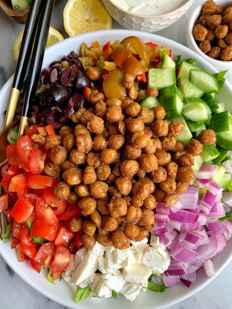 This Vegetarian Greek Salad with Tahini Yogurt Dressing is filled with all your Greeks salad favorites plus it's topped with crispy chickpeas and tossed in a delicious tahini yogurt dressing. 