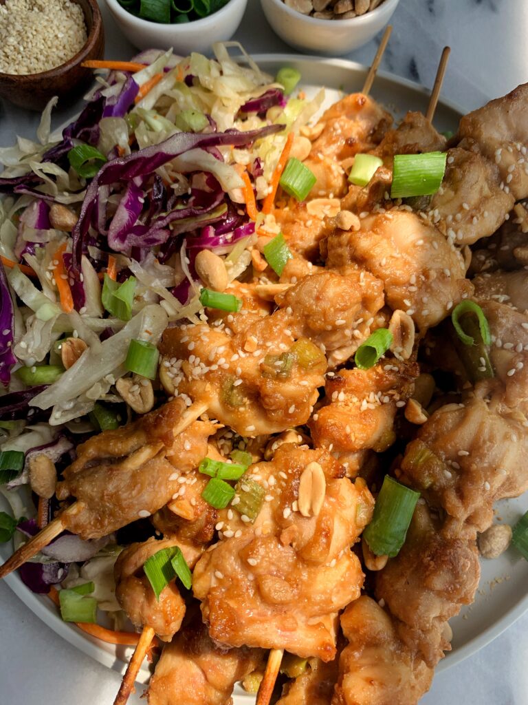 Chicken skewers topped with peanut sauce paired with an asian inspired slaw