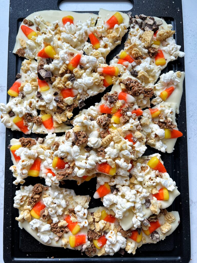 This Halloween Monster Munch Bark is the ultimate snack to make for Halloween! White chocolate base topped with popcorn, candy corn, pumpkin granola and more for the ultimate sweet and salty snack.